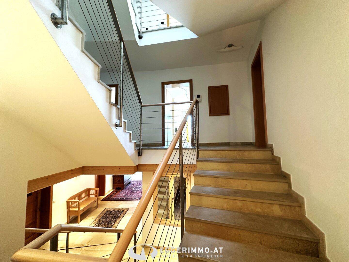 Mehrstöckige Treppe mit Holzstufen und modernen Metallgeländern, die das Haus verbindet.