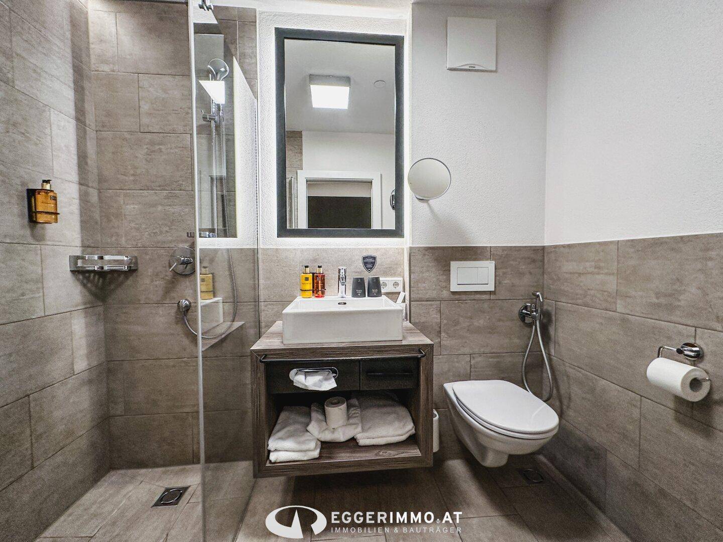 Modernes Badezimmer mit ebenerdiger Dusche, Wand-WC und stilvollen Fliesen.