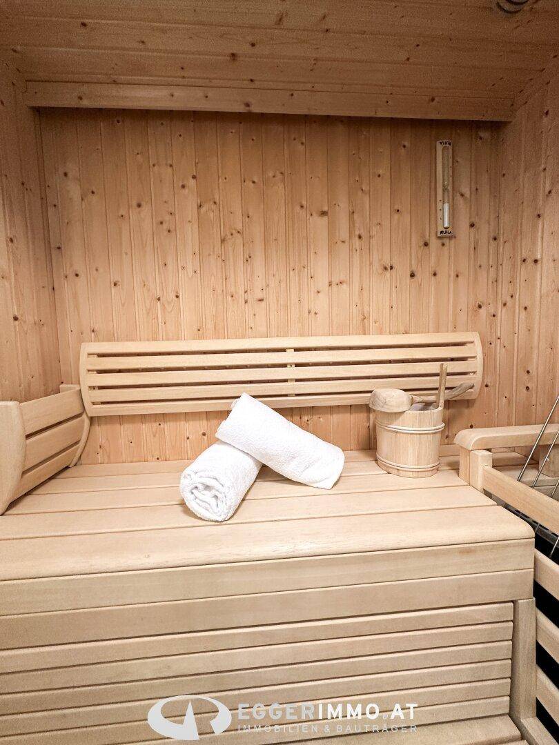Private Sauna mit Holzbänken und traditionellem Aufgusseimer für Entspannung.