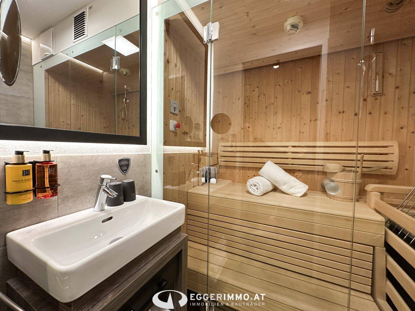 Modernes Badezimmer mit Waschbecken und direktem Zugang zur privaten Sauna.