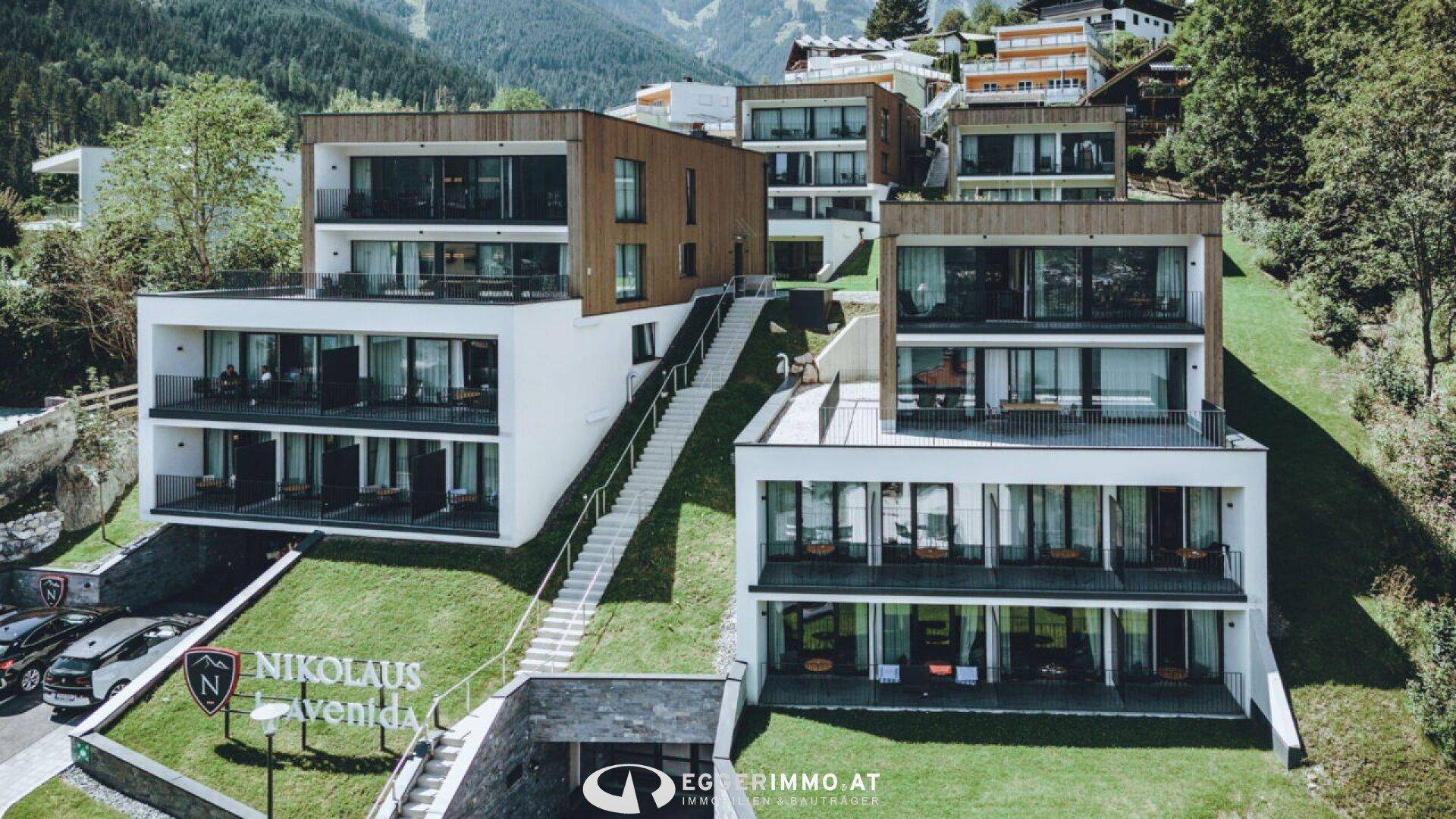 Zeitgenössische Apartmenthäuser mit Holzfassaden und großen Glasfronten in alpiner Umgebung.