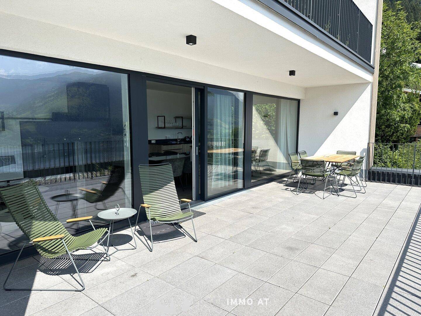 Große Terrasse mit Schiebetüren zum Innenbereich und bequemen Lounge-Stühlen, ideal für Entspannung im Freien.