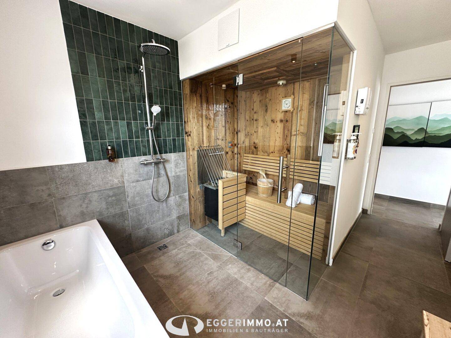 Geräumiges Badezimmer mit Badewanne und einer eleganten, gläsernen Sauna für entspannende Momente.