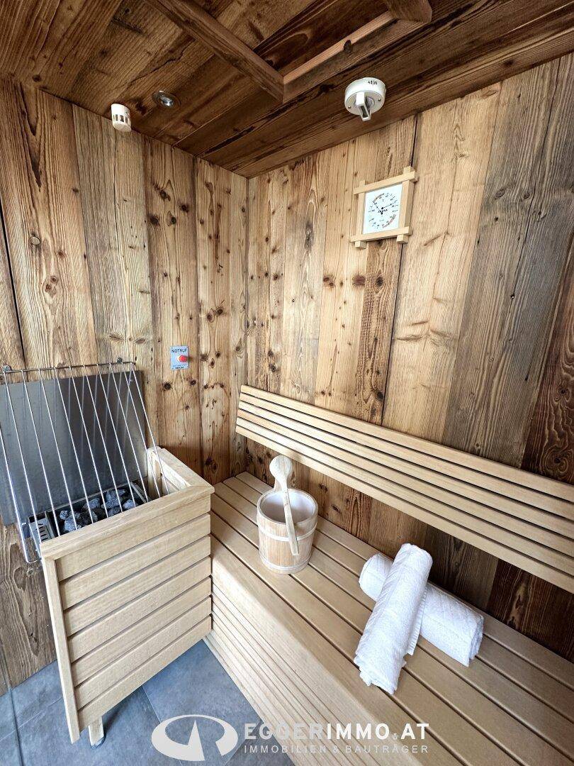 Innenansicht der Holzsauna mit bequemen Bänken und traditionellem Saunaofen, bereit zur Nutzung.