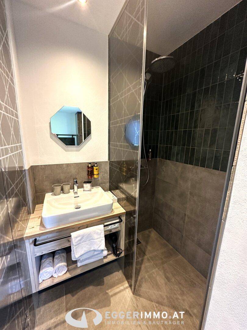 Kompaktes Badezimmer mit modernem Waschtisch und einer begehbaren Dusche mit Glasabtrennung.