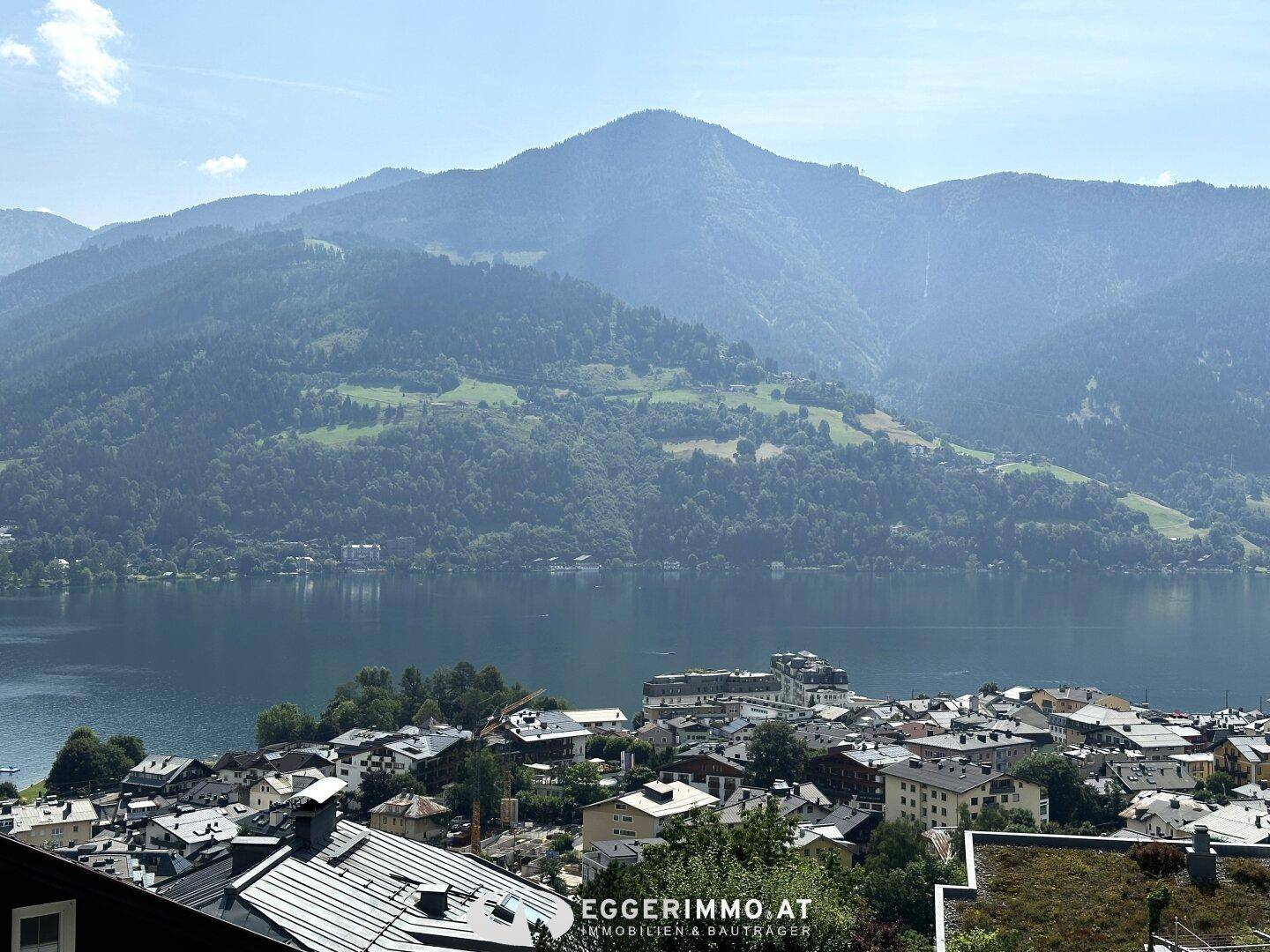 Panoramablick auf einen malerischen See mit einer Stadt am Ufer, umgeben von majestätischen Bergen.