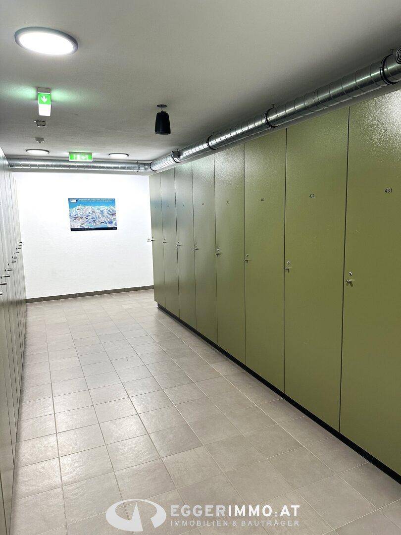 Geräumiger Skiraum mit Reihen von grünen Schließfächern und Fliesenboden, ideal zur Aufbewahrung.