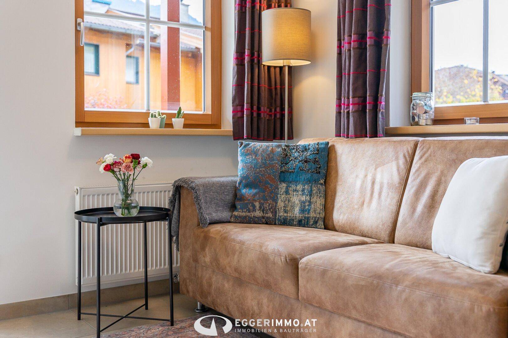 Gemütlicher Wohnbereich mit braunem Sofa, Fensterblick und dekorativen Kissen.