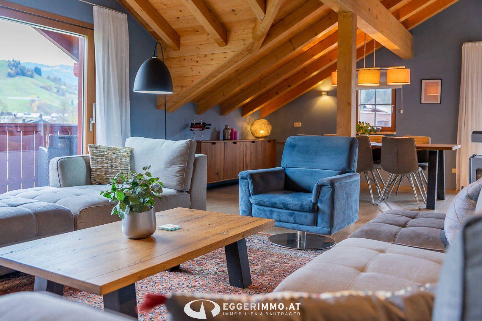 Offener Wohn- und Essbereich mit Holzbalkendecke, gemütlichen Sofas und Bergblick.