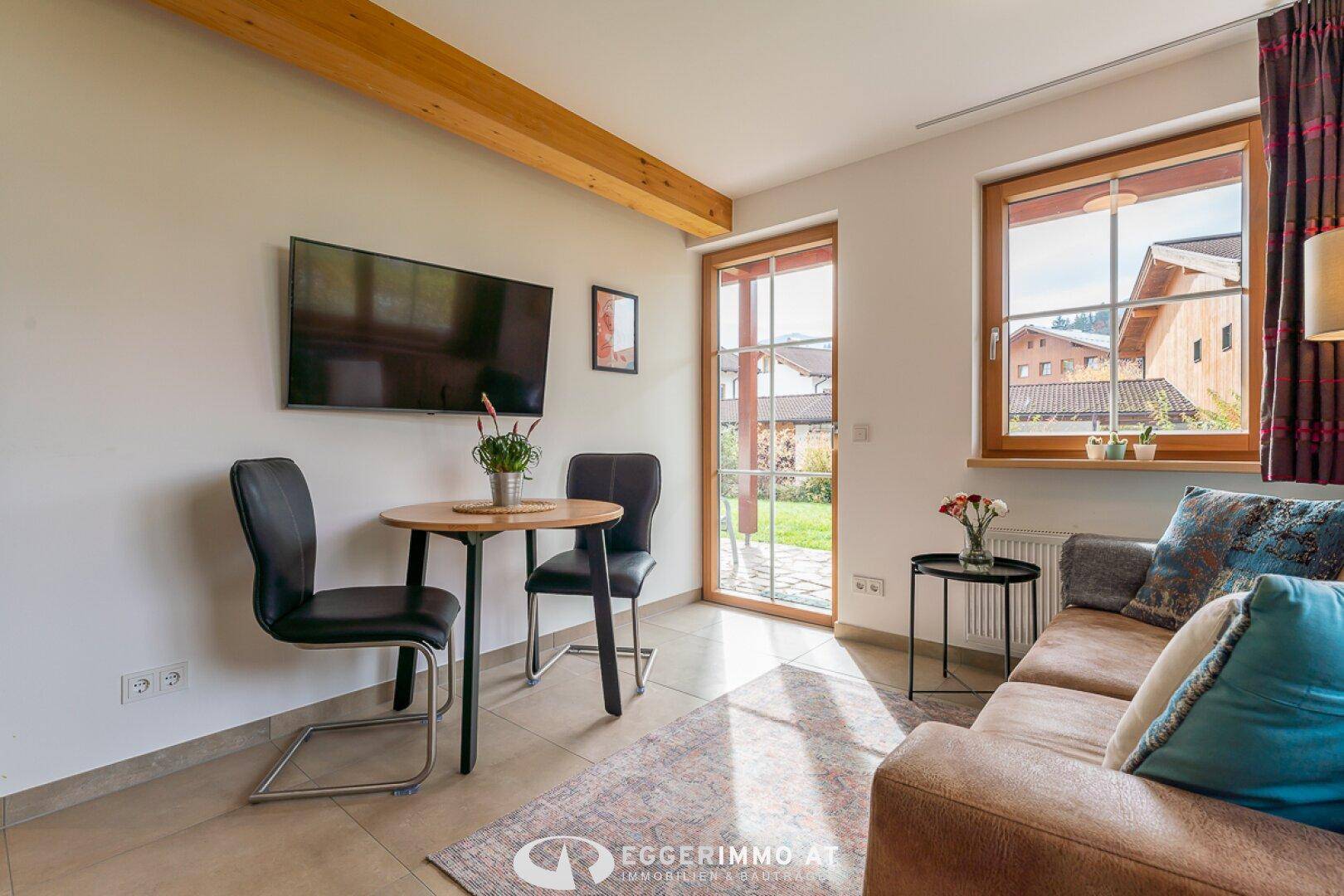 Gemütlicher Wohnbereich mit Sofa, Esstisch und Zugang zum Garten oder Terrasse.