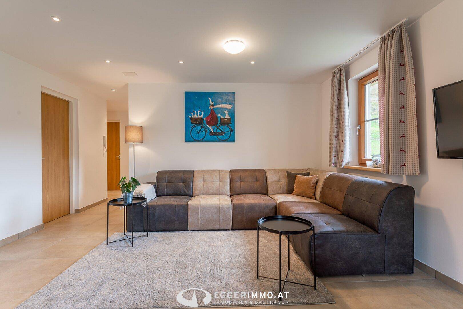 Heller Wohnbereich mit großem Ecksofa, modernem Teppich und Kunst an der Wand.
