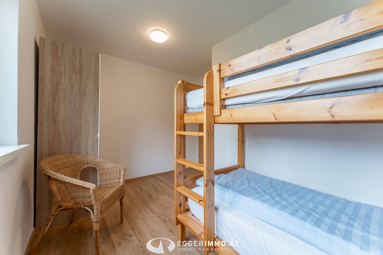 Kinderzimmer mit Etagenbett, Holzfußboden und hellem Ambiente.