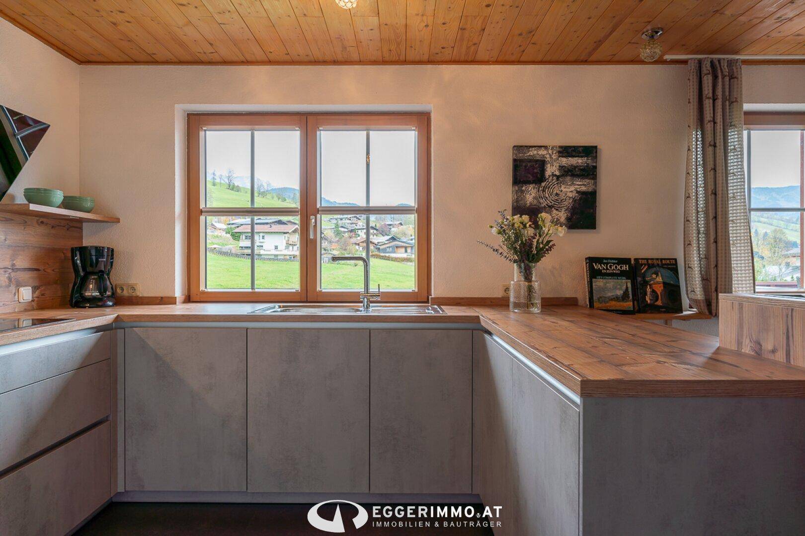 Moderne Küche mit Holzarbeitsplatten, Spüle und Fenster mit Blick auf die grüne Landschaft.