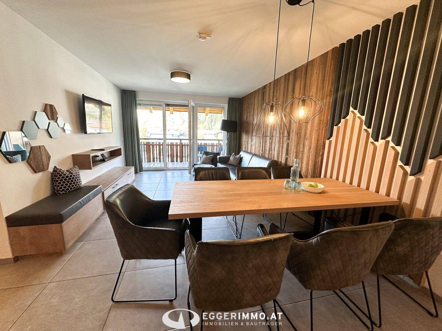 Geräumiger offener Wohn-Essbereich mit Sofa, Esstisch und Zugang zum Balkon.