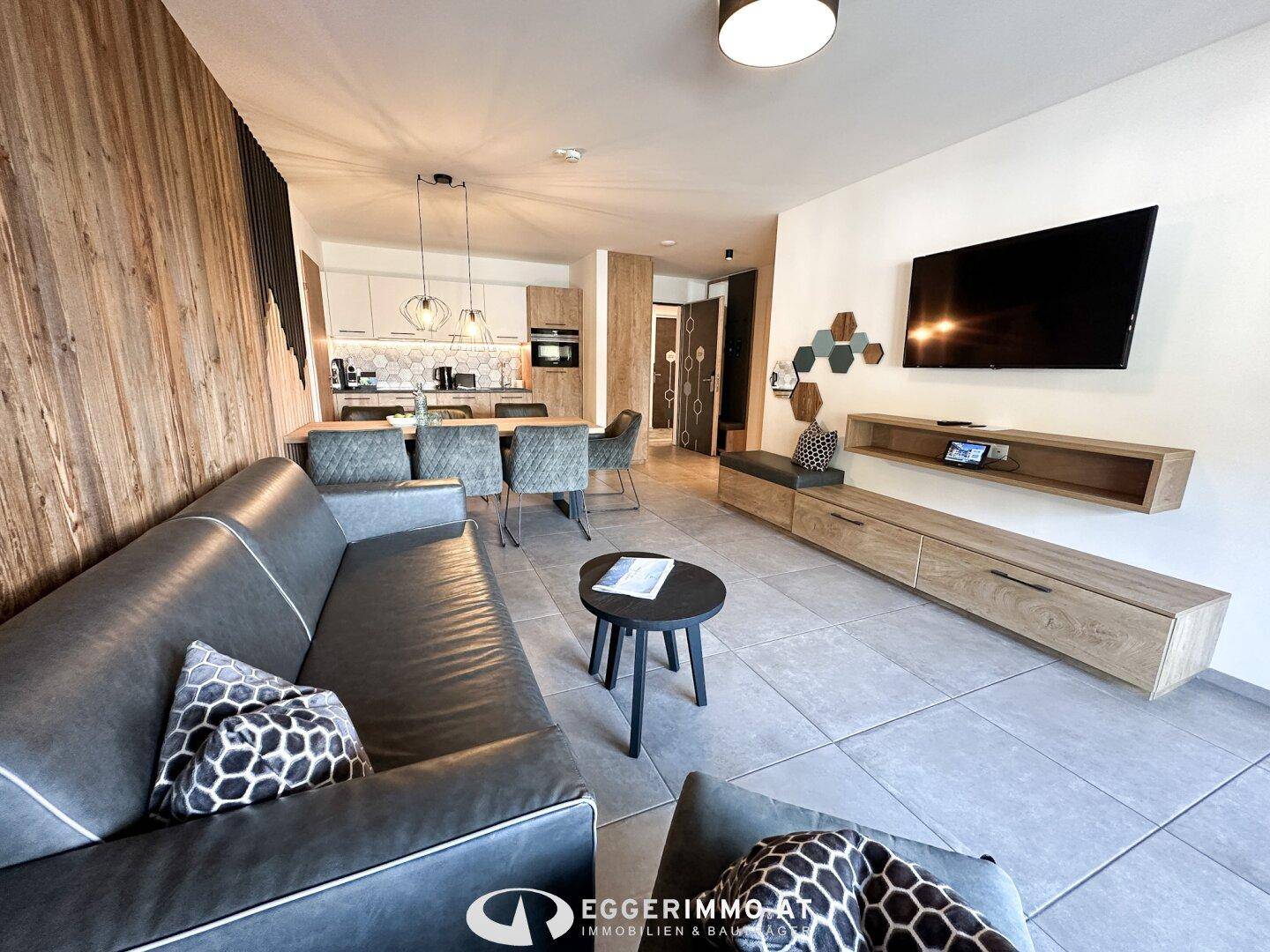 Offener Wohnbereich mit Sofa, Esstisch und integrierter Küche in modernem Design.