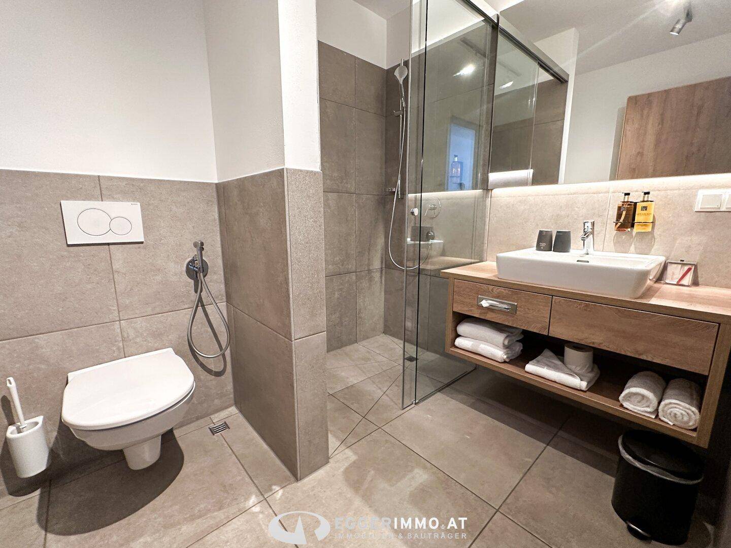 Modernes Badezimmer mit Waschtisch, begehbarer Dusche und Wand-WC.