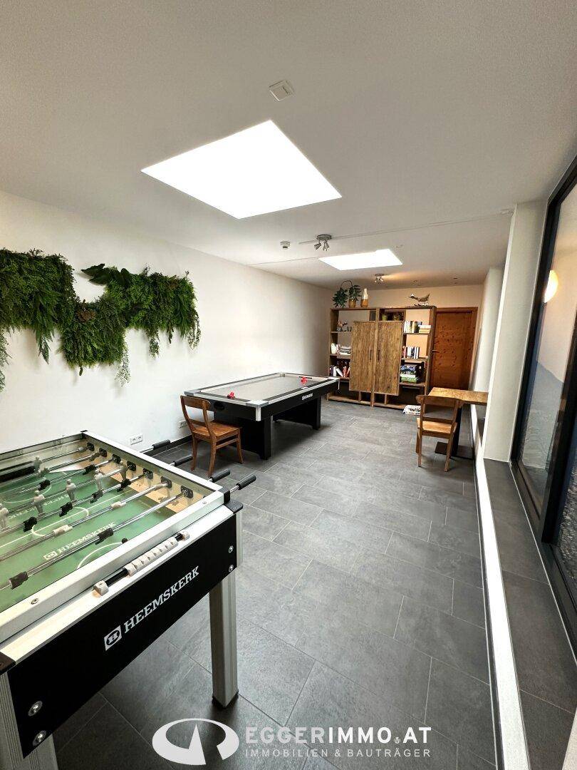 Heller Freizeitraum mit Billardtisch, Tischfußball und großen Fenstern, die viel Tageslicht hereinlassen.