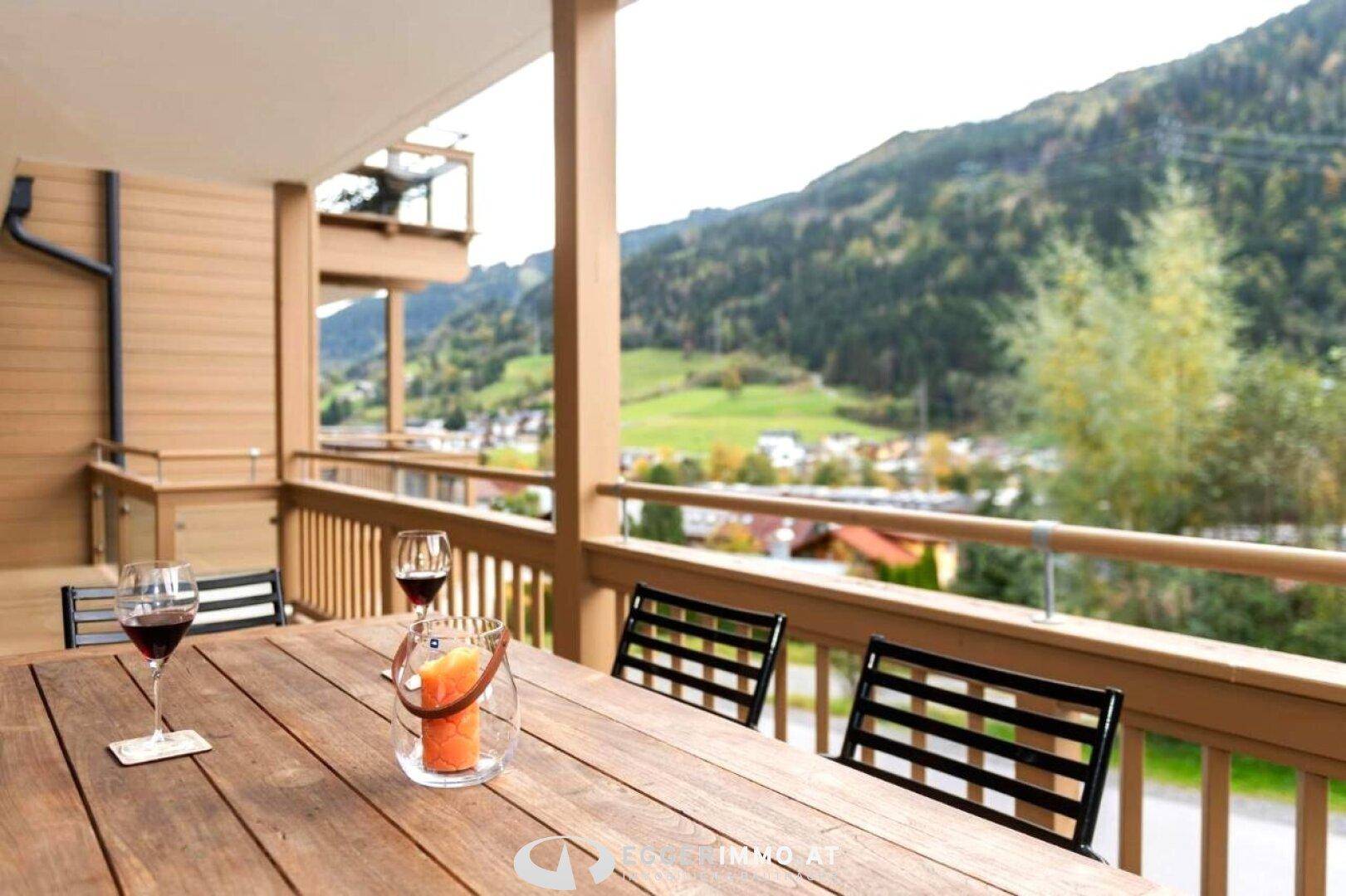 Geräumiger Balkon mit Holztisch, Stühlen und Panoramablick auf die Berge und das Tal, ideal zum Entspannen.