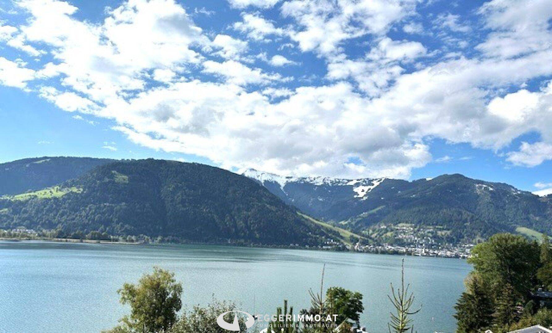 Weitläufiger Blick auf den See und die majestätischen Berge unter einem weiten blauen Himmel.