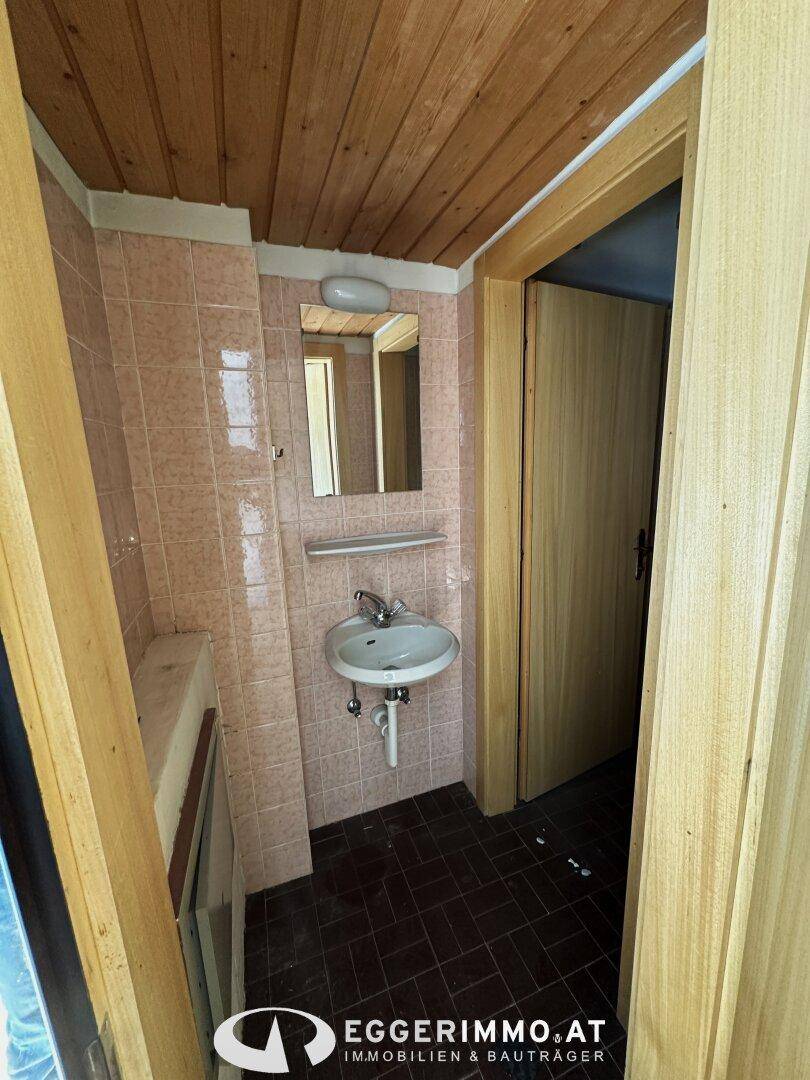 Kleines Badezimmer mit rosa Fliesen, Holzdecke und einem Waschbecken.