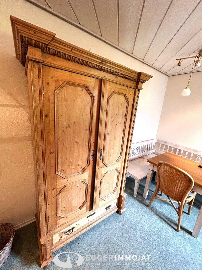 Detailansicht eines großen, traditionellen Holzschranks mit Schnitzereien im Schlafzimmer.