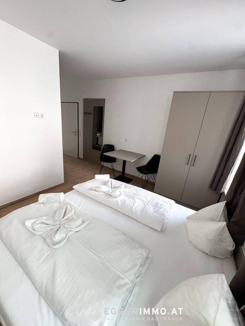 Gemütliches Schlafzimmer mit Doppelbett, Kleiderschrank und kleinem Esstisch.