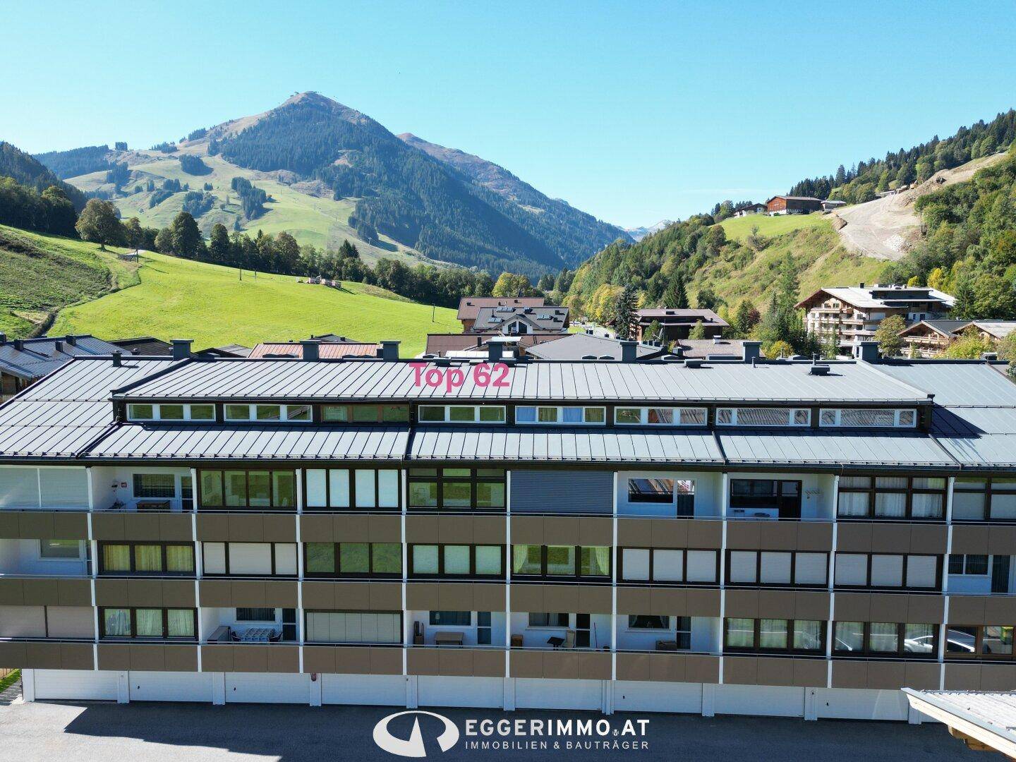 Gebäudeansicht mit mehreren Etagen und Balkonen vor einer malerischen Berglandschaft.