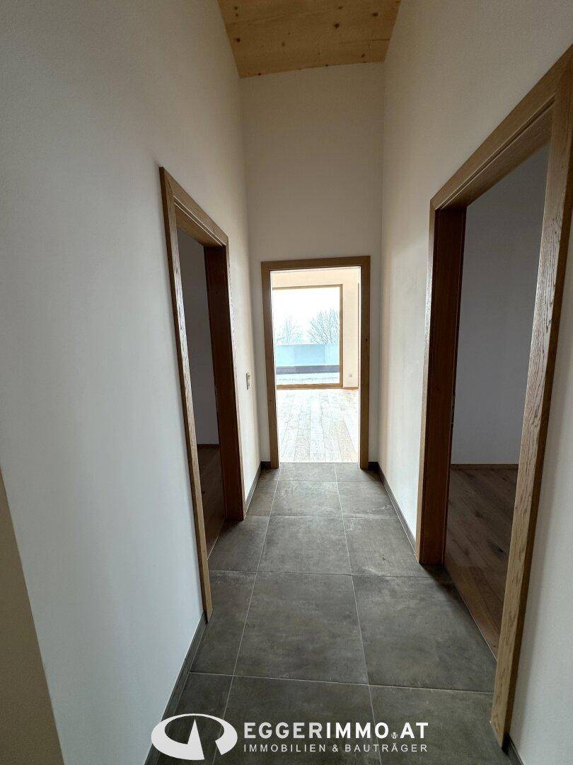 Langer Flur mit Fliesenboden und Holztüren, der verschiedene Wohnbereiche verbindet.