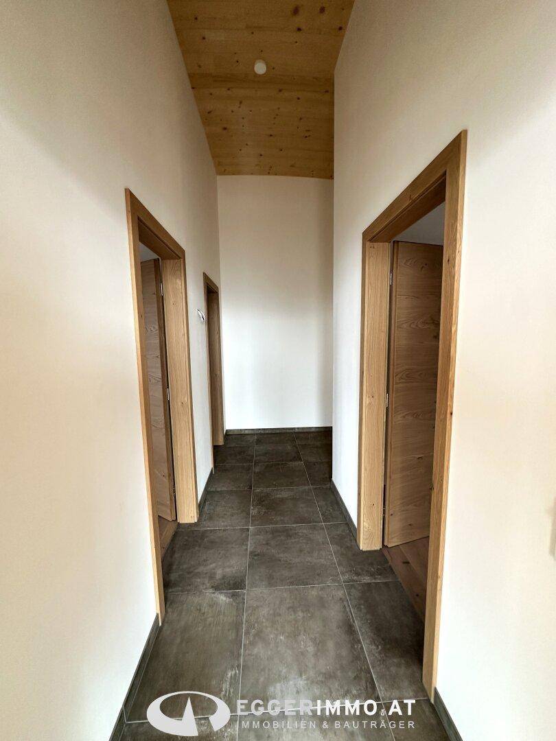 Flur mit Fliesenboden und Holztüren, der zu den privaten Räumen der Wohnung führt.