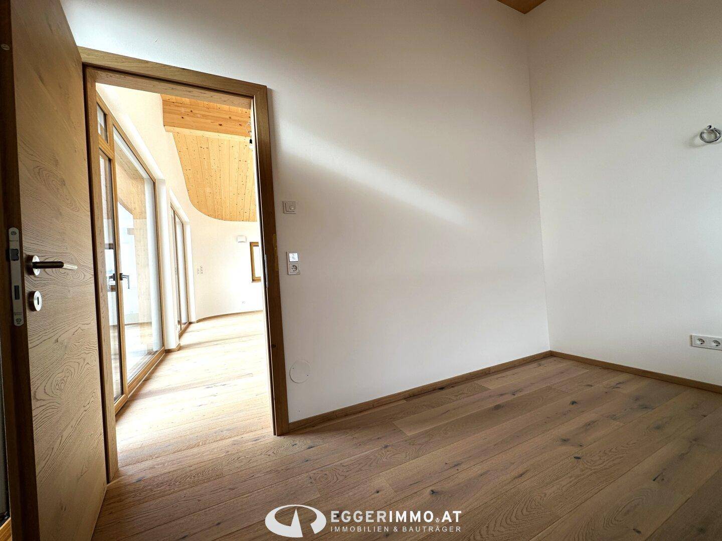 Geräumiges Zimmer mit Holzboden und Zugang zum Hauptwohnraum, ideal für Schlaf- oder Arbeitszimmer.