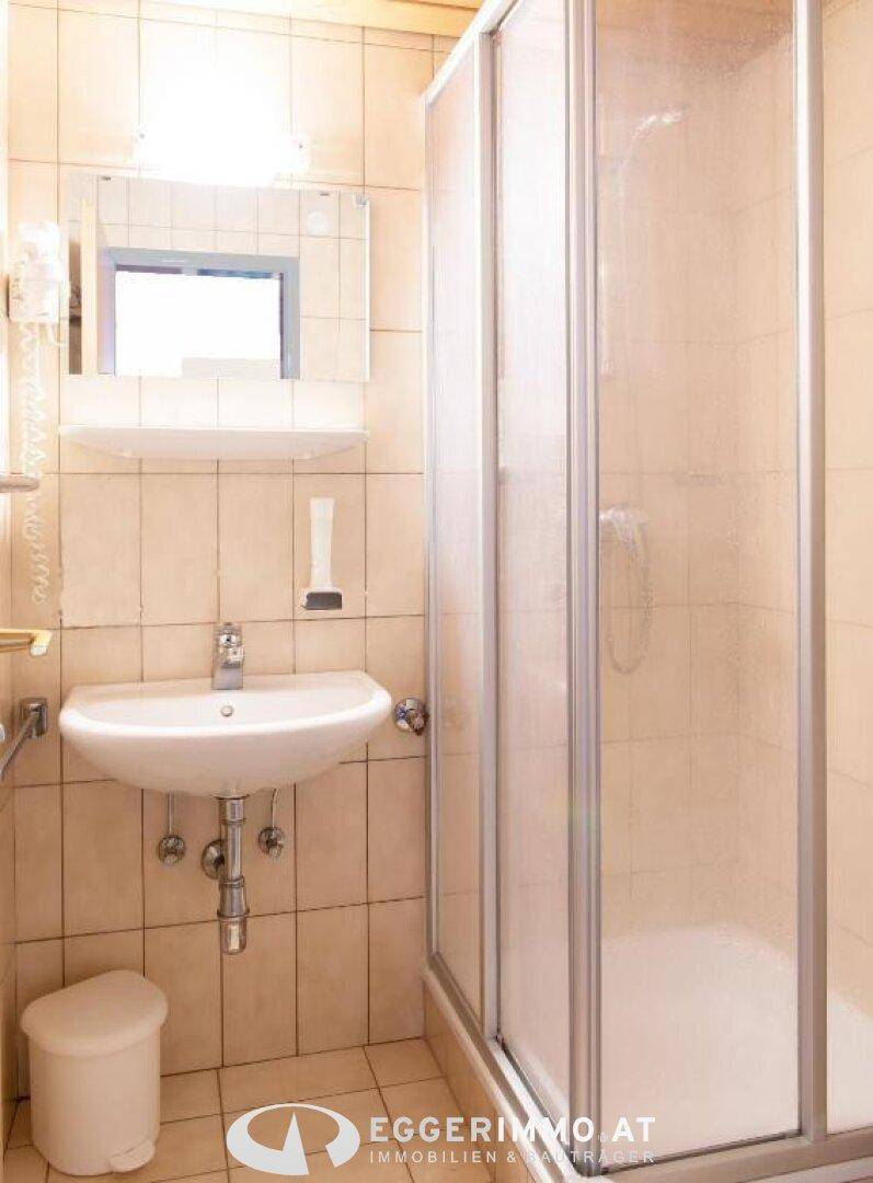 Funktionales Badezimmer mit Duschkabine, Waschbecken und Fliesenboden, inklusive Fenster.