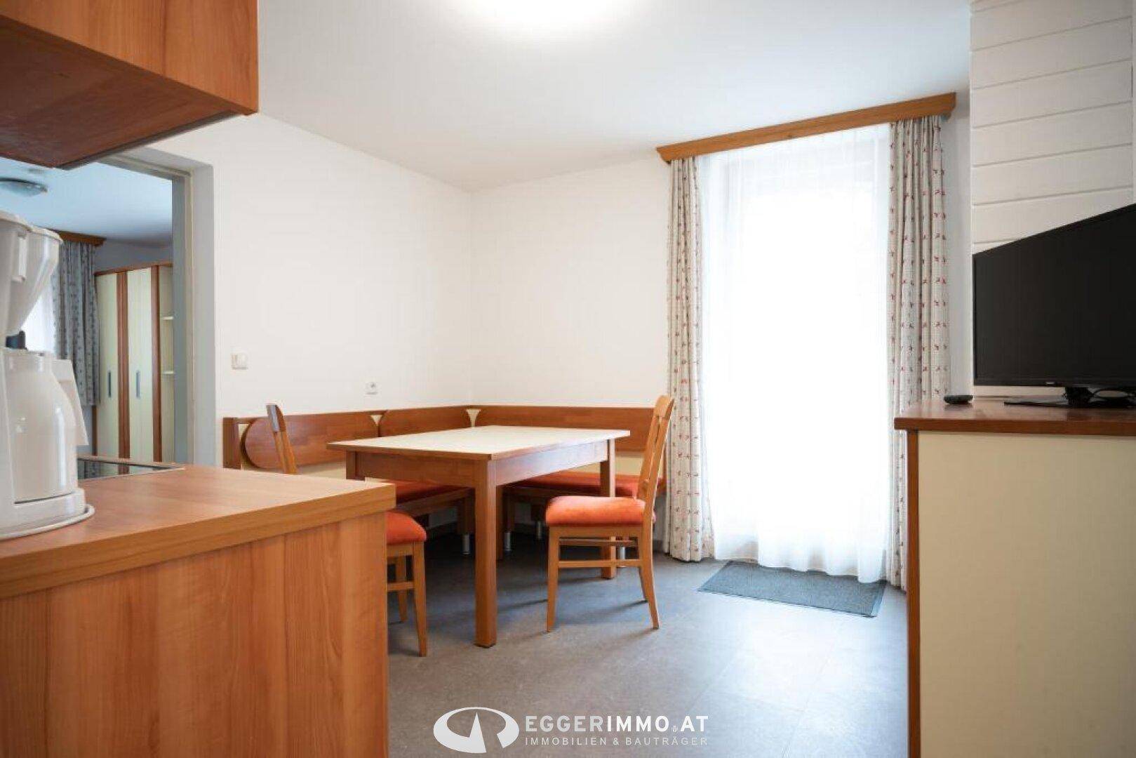 Heller Essbereich mit Holztisch, Eckbank und Kaffeemaschine, direkt am Fenster gelegen.