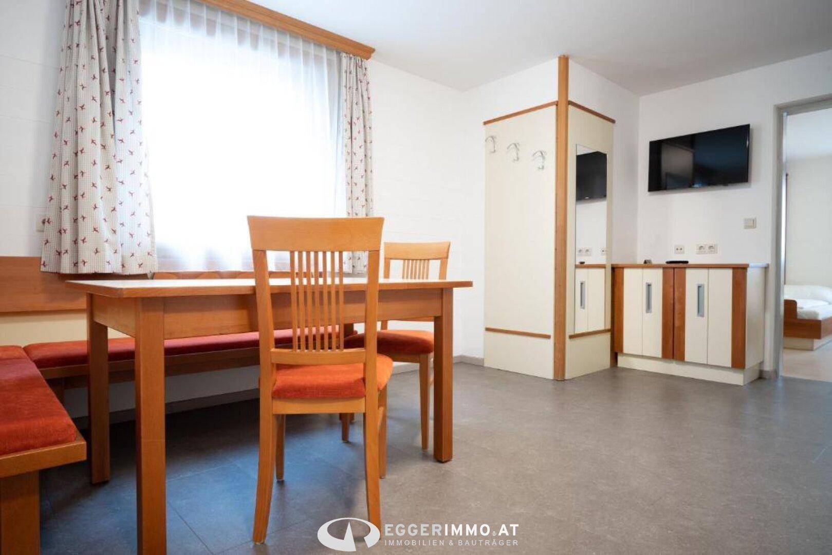 Geräumiger Essbereich mit Holztisch und Eckbank, angrenzend an einen Eingangsbereich mit Garderobe.