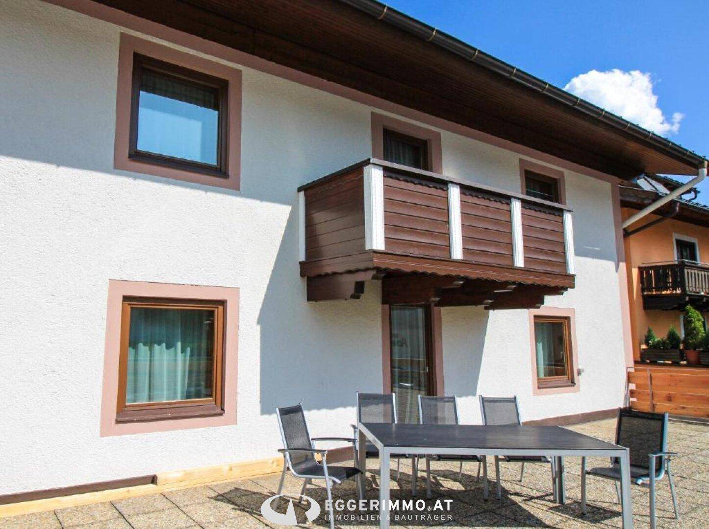 Traditionelles Gebäude mit Balkon und einer gepflasterten Terrasse, möbliert für den Außenbereich.