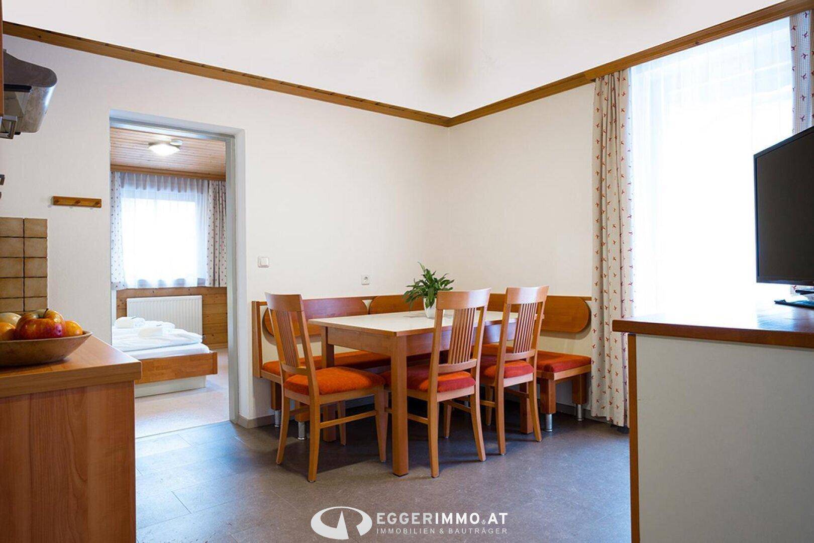 Gemütlicher Essbereich mit Holztisch, Eckbank und Stühlen, angrenzend an einen weiteren Raum.