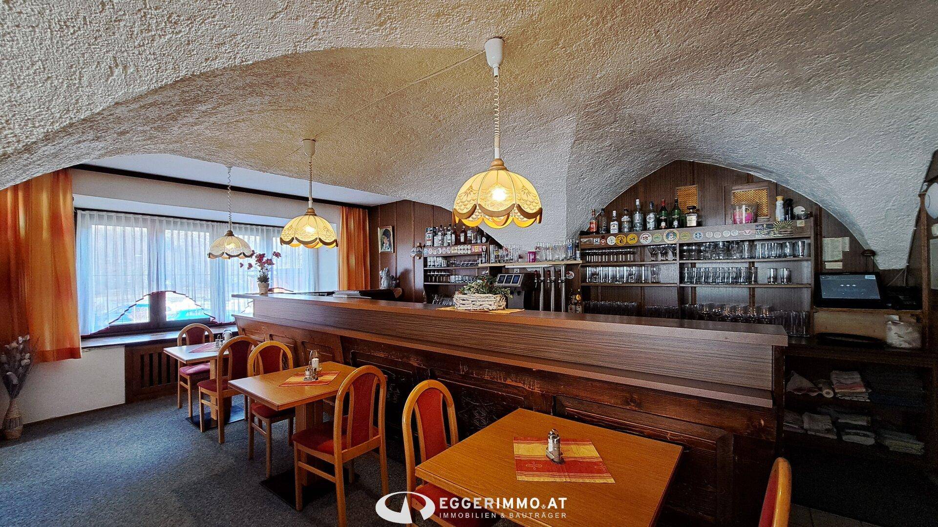 Traditionelle Bar mit gewölbter Decke, Holztheke und Regalen voller Flaschen und Gläser.