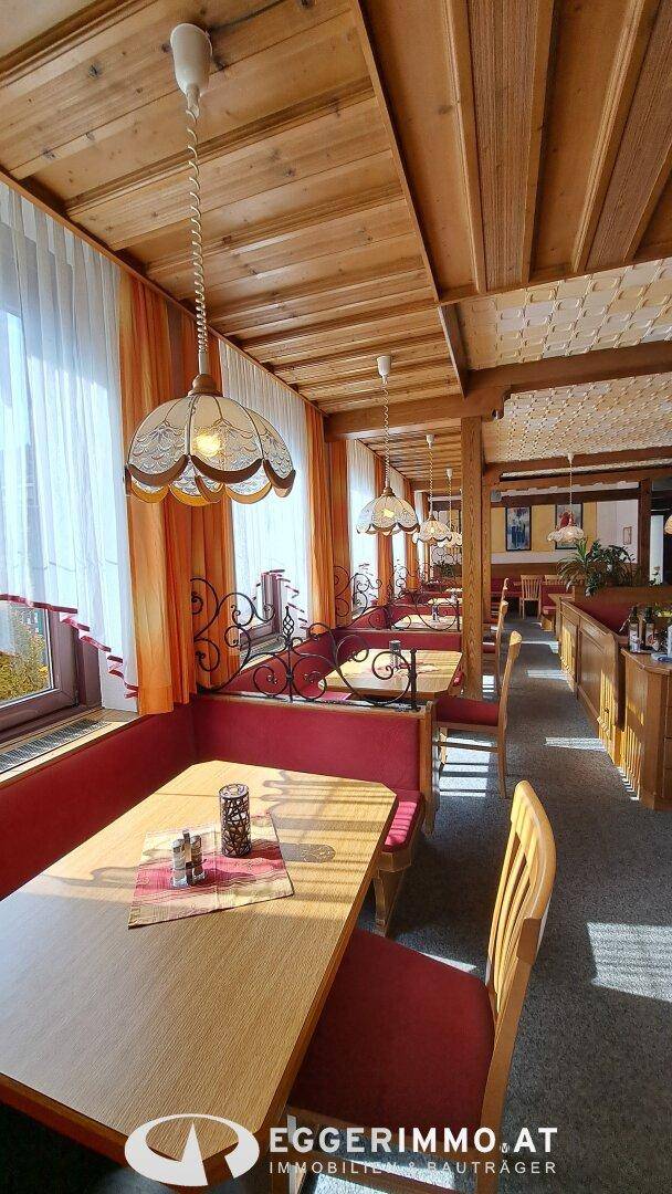 Gemütlicher Restaurantbereich mit Holztäfelung, roten Sitzbänken und traditionellen Deckenleuchten.