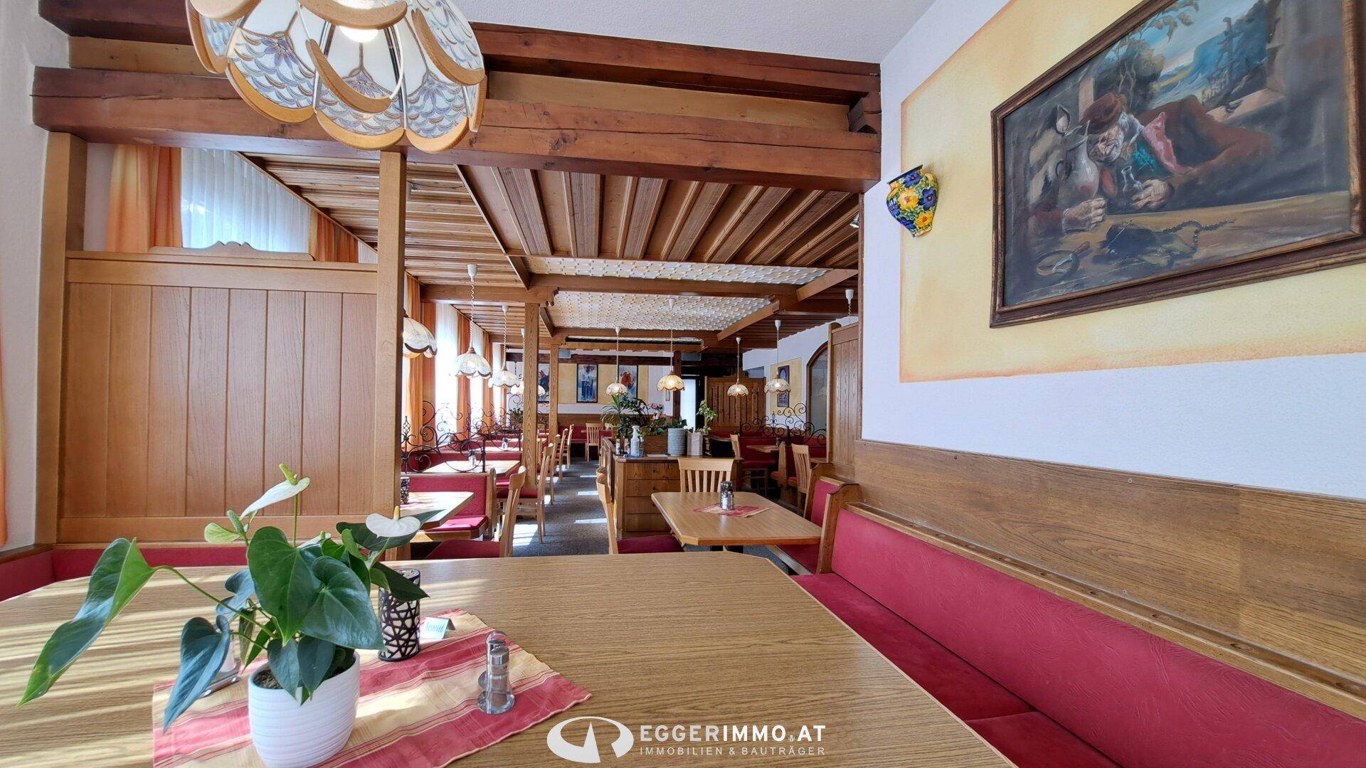 Geräumiger Restaurantbereich mit Holzbalken, roten Sitzbänken und traditioneller Wanddekoration.