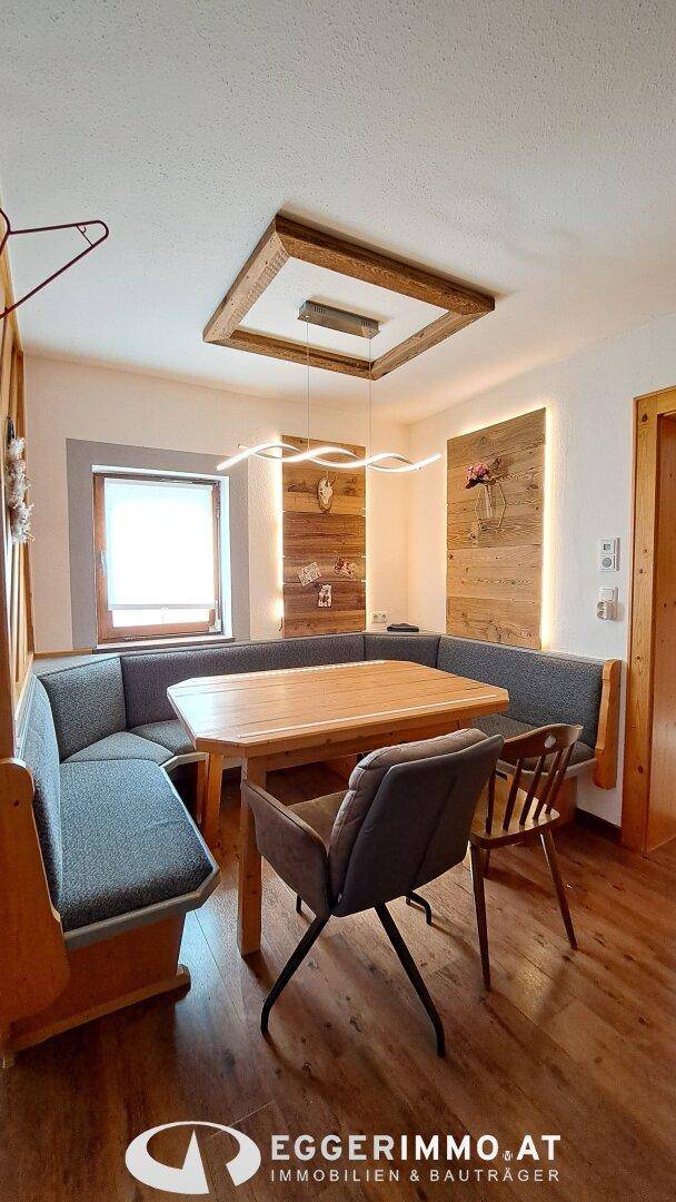 Gemütlicher Essbereich mit Eckbank, Holztisch und dekorativer Holzverkleidung an den Wänden.