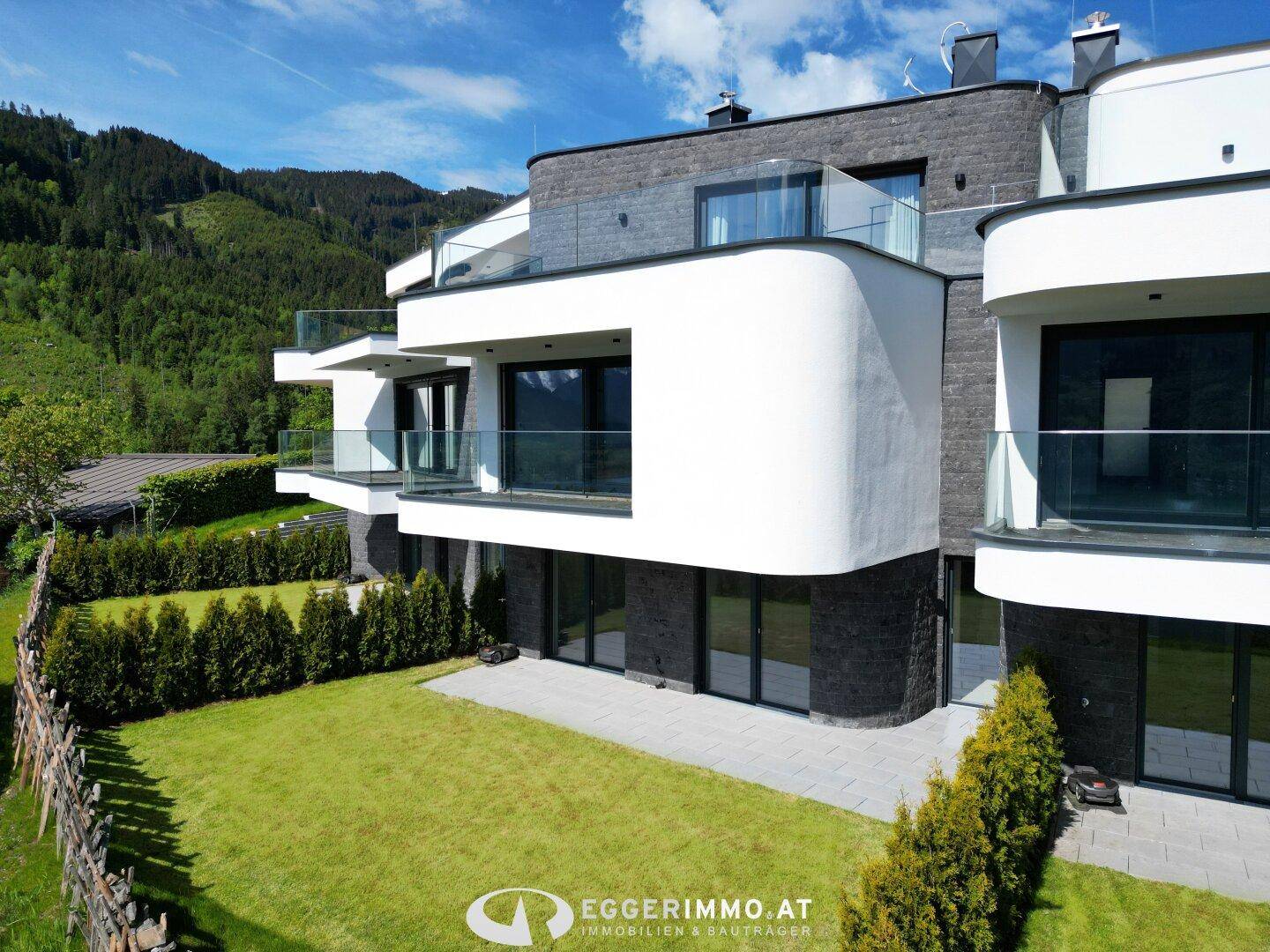 Moderne Architektur mit geschwungenen Balkonen und gepflegtem Rasenbereich.