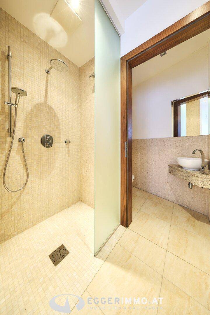 Modernes Badezimmer mit begehbarer Dusche, Mosaikfliesen und einem stilvollen Waschbecken.