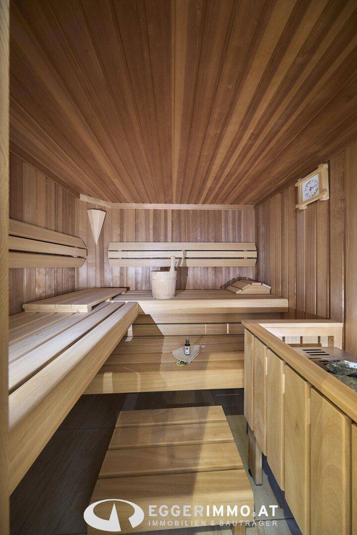 Traditionelle Holzsauna mit mehreren Bänken und klassischem Saunaofen für entspannende Momente.
