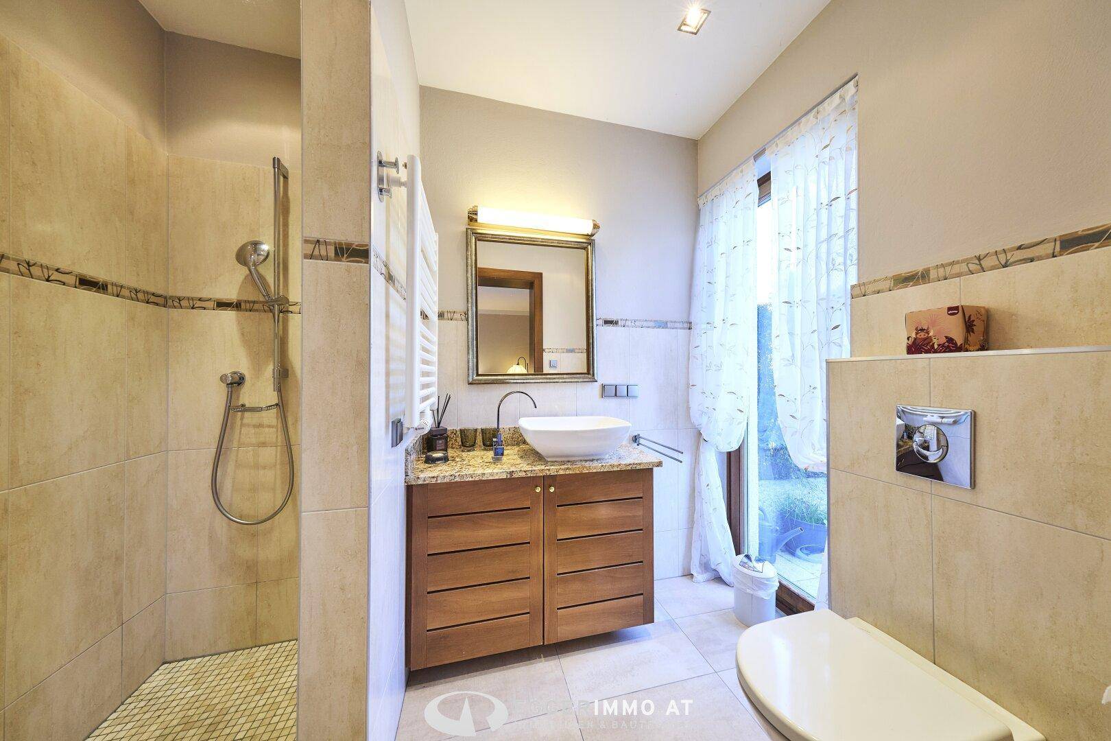 Modernes Badezimmer mit begehbarer Dusche, WC, Waschbecken und Fenster für Tageslicht.