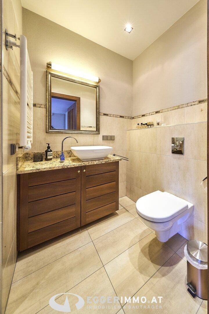 Elegantes Badezimmer mit wandhängendem WC, modernem Waschbecken und Granit-Waschtischplatte.
