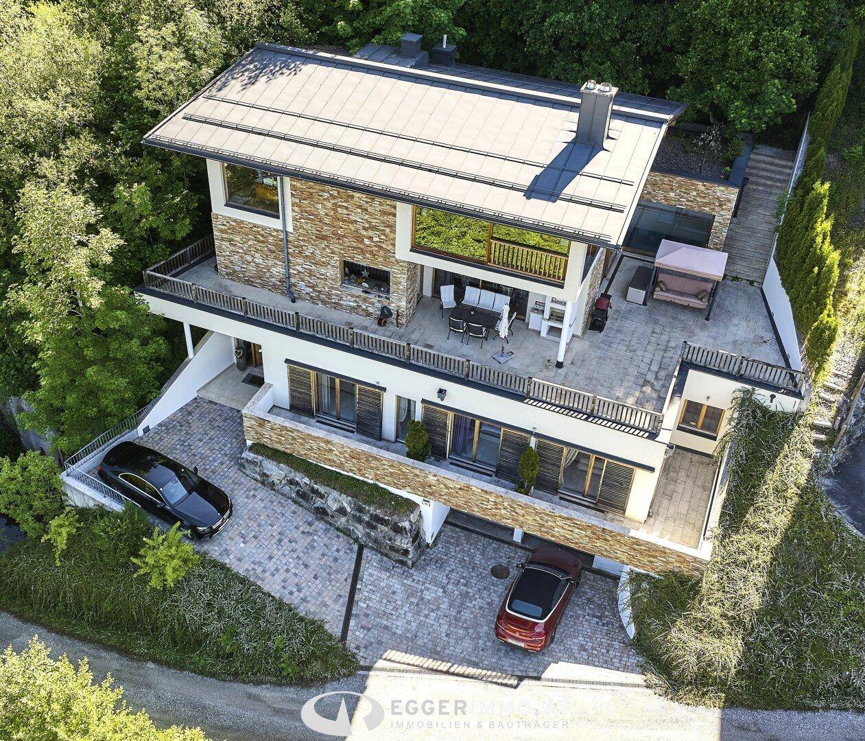 Luftaufnahme des Anwesens mit großzügigen Terrassen, Zufahrt und umgebender Natur.