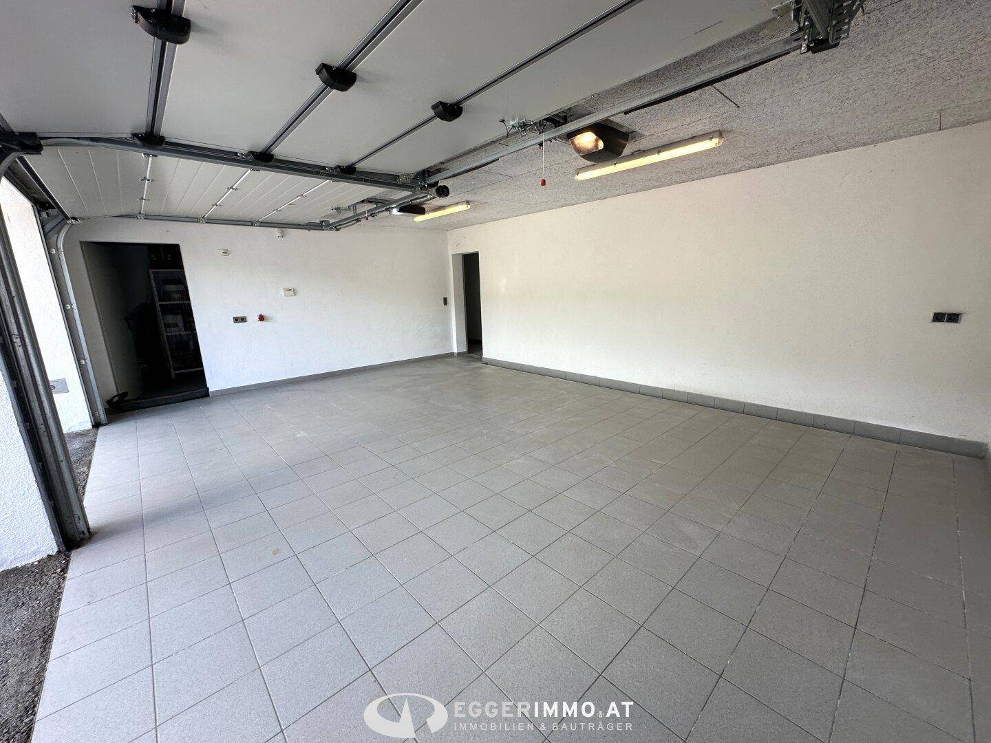 Geräumige Garage mit gefliestem Boden und viel Platz für Fahrzeuge und Lagerung.