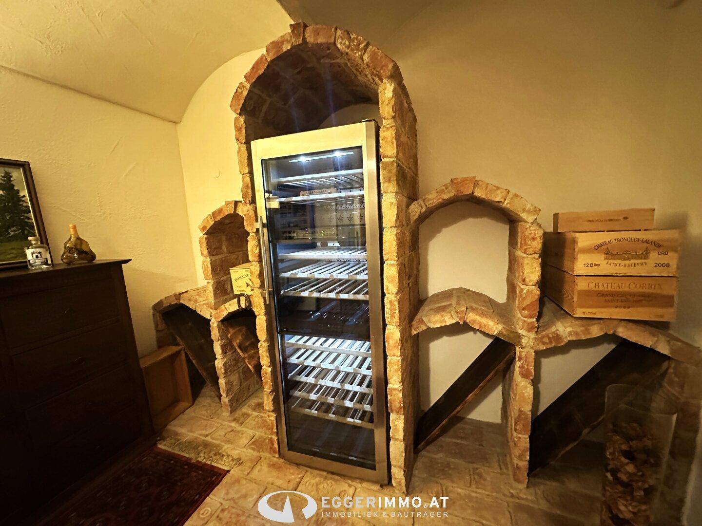 Gemütlicher Weinkeller mit traditionellen Ziegelbögen und einem modernen Weinkühlschrank.