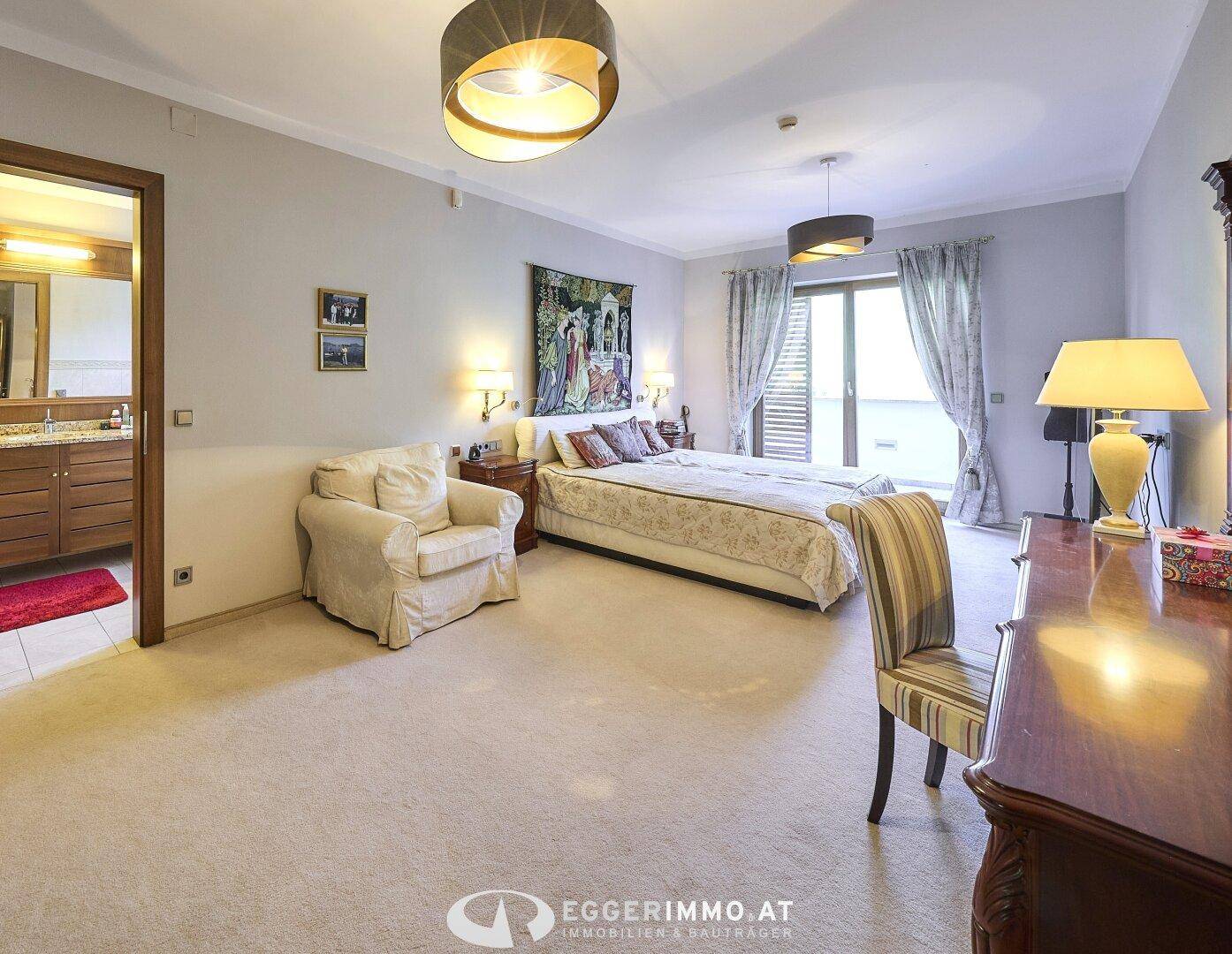 Geräumiges Schlafzimmer mit Teppichboden, großem Bett und direktem Zugang zum luxuriösen Badezimmer.