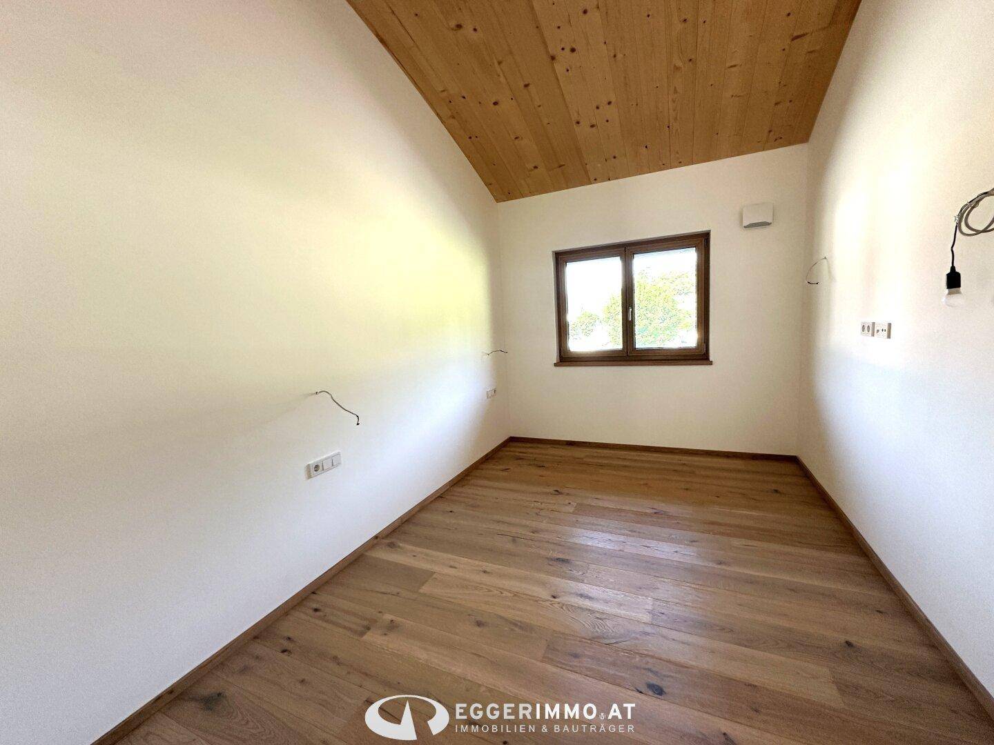 Unmöbliertes Zimmer mit Holzboden und Holzdecke, ideal für Schlafzimmer oder Arbeitsbereich.