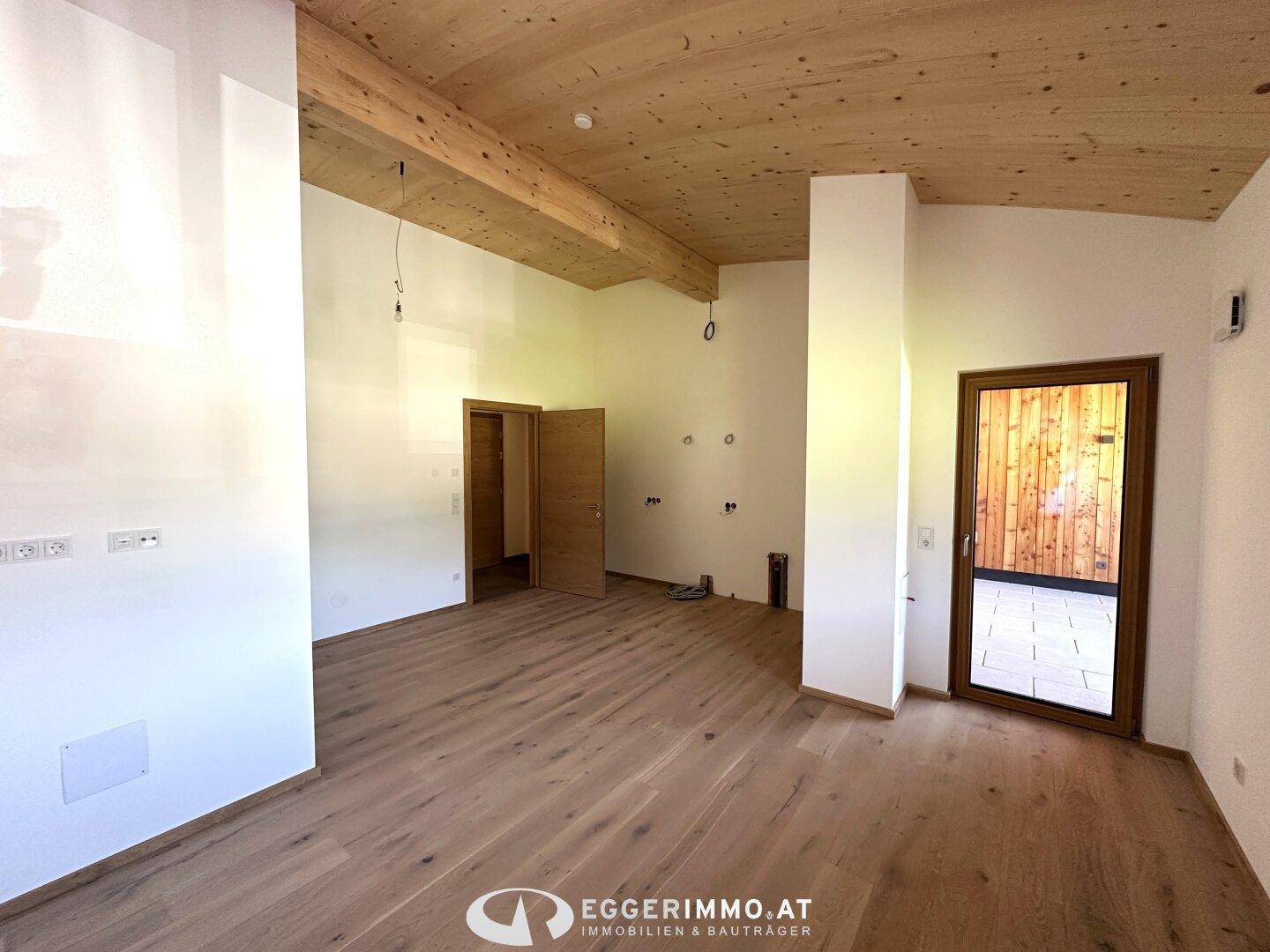 Geräumiger Innenraum mit Holzbalken und Holzboden, ideal für einen offenen Wohnbereich.